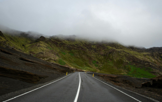 A curvy road along the base of a mountain range.