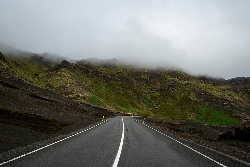 A curvy road along the base of a mountain range.