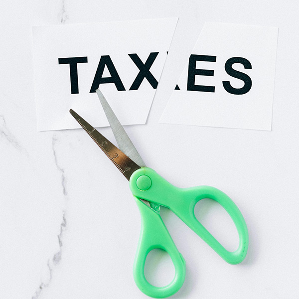 Tax Deductions A piece of paper with the word "taxes" printed on it, cut in half next to a pair of scissors.